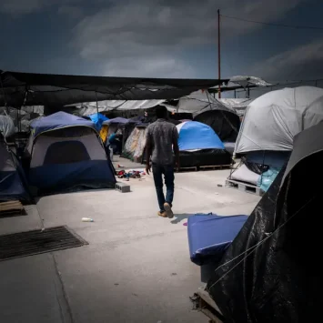 Un hombre caminando entre las tiendas de campaña de un campamento para personas migrantes en Reynosa.