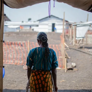 Una mujer se encuentra en la puerta de la clínica de MSF donde se atiende a víctimas y sobrevivientes de violencia sexual en el campo de personas desplazadas de Bulengo, Kivu Norte, República Democrática del Congo, agosto de 2023. © Alexandre Marcou/MSF