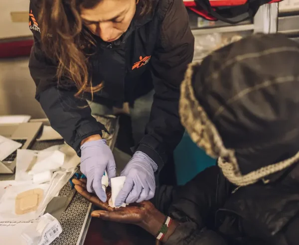 Personal de Médicos Sin Fronteras hace curación en la mano de un migrante menor no acompañado