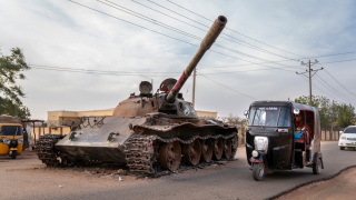 Un taxi rickshaw rodea un tanque destruido de las Fuerzas Armadas sudanesas.