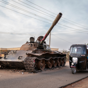 Un taxi rickshaw rodea un tanque destruido de las Fuerzas Armadas sudanesas.