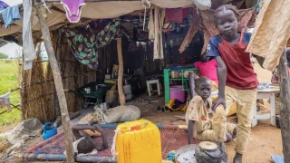 Los hijos de Elizabeth frente a su refugio en la carretera en Abyei, tras la inundación que sumergió su anterior hogar el 22 de agosto.