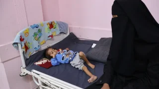 Una madre sentada con su hijo desnutrido en el hospital Nasser, que cuenta con el apoyo de MSF.